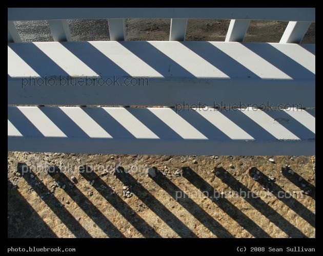 Guardrail - A sidewalk guardrail on a bridge, with diagonal shadows from vertical fence poles, Fitchburg MA