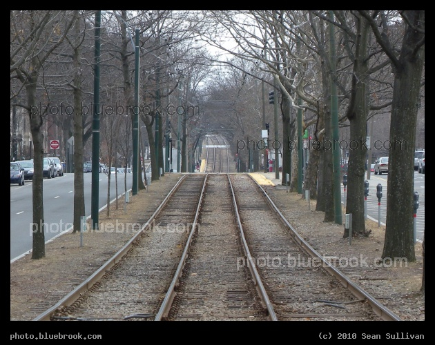 Tunnel of Trees - Looking west along the Green Line streetcar tracks in the center of Beacon Street, Brookline MA.  The view is from the Hawes Street station, and platforms at the next two stations are visible - Kent Street and St Paul Avenue.