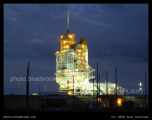 Pad 39-A Illuminated - Kennedy Space Center launch pad 39-A during predawn twilight, illuminated by floodlights, with shuttle Discovery under the rotating service structure