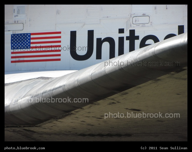 United - A close-up view of the left wing of space shuttle Atlantis, and the insigna on the payload bay, during transfer to the VAB for flight STS-135