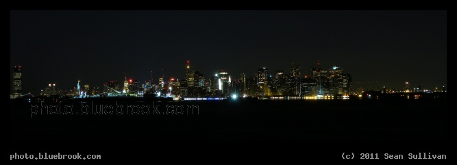 Manhattan at Night - A view of the Manhattan skyline before sunrise from Staten Island.  Jersey City and the Statue of Liberty are visible on the left, and Brooklyn Bridge is on the right.