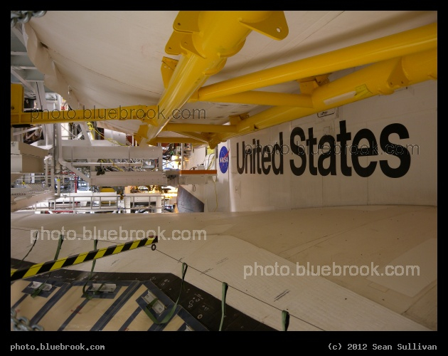 Payload Bay Doors - A view of space shuttle Discovery in the Orbiter Processing Facility hangar, from a level between the right wing (below) and the open payload bay doors (above).  The yellow structure supports the payload bay doors on Earth, which are designed to open in weightlessness.